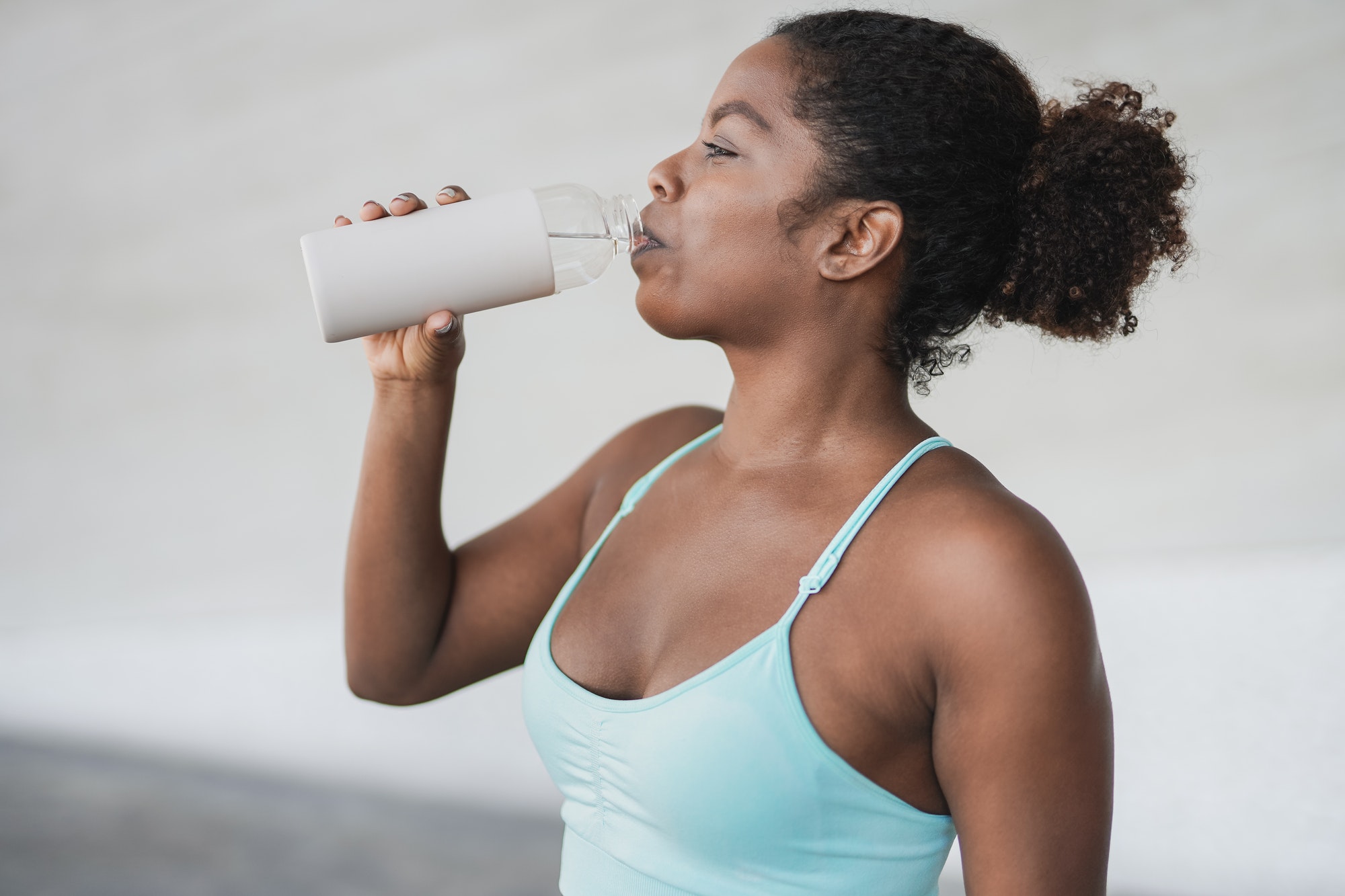 Fit african girl drinking water after sport workout outdoor